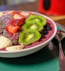 An acai bowl topped with kiwi, bananas, and strawberries