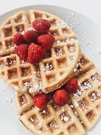 Waffles topped with powedered sugar and raspberries